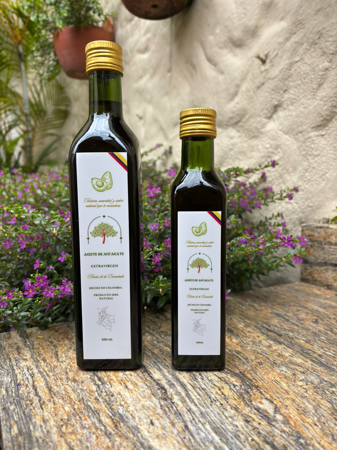 Botellas de aceite de aguacate Frutos de la Encantada entre flores, para el cuidado de la piel y el cabello
